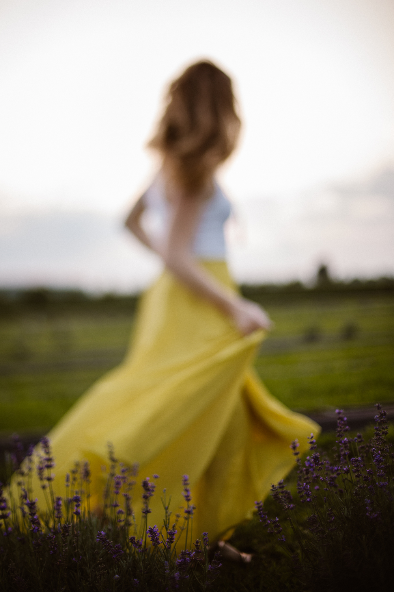 Red headed woman in yellow skirt at sunset in a lavender field.